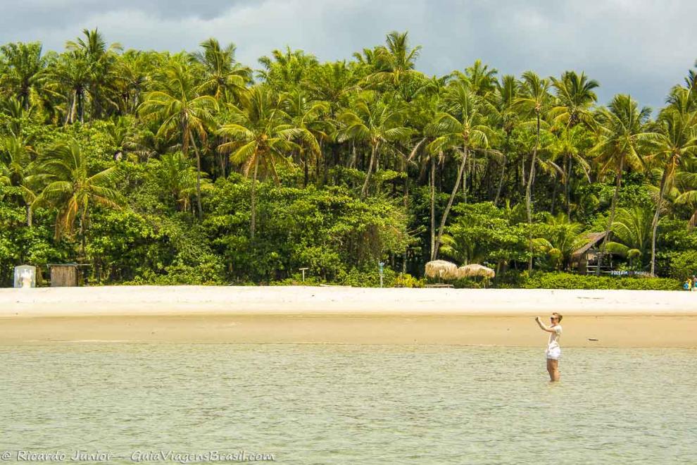 Imagem de uma turista registrando as belezas da Praia de Moreré.